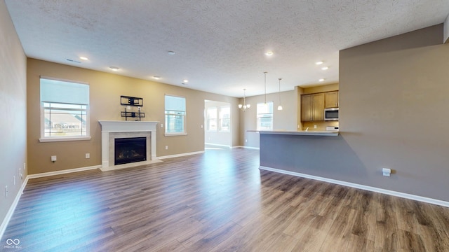 unfurnished living room with dark hardwood / wood-style flooring and a textured ceiling