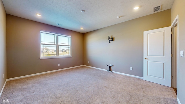 carpeted empty room featuring a textured ceiling