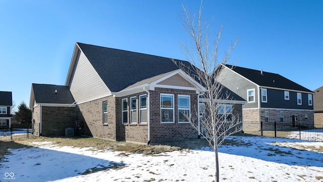 snow covered house featuring central AC unit