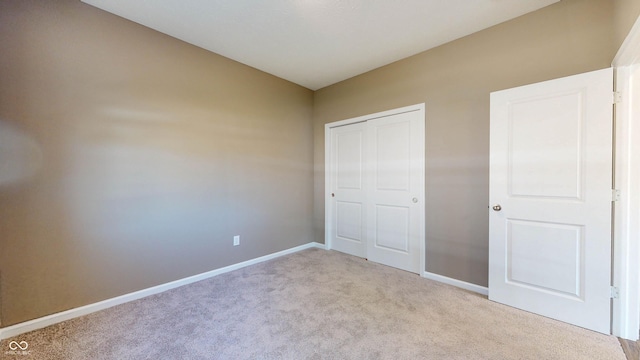 unfurnished bedroom featuring light colored carpet and a closet