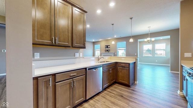 kitchen featuring decorative light fixtures, dishwasher, sink, light hardwood / wood-style floors, and kitchen peninsula