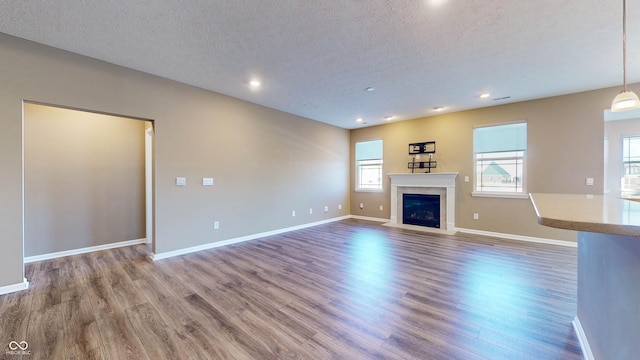 unfurnished living room with wood-type flooring and a textured ceiling