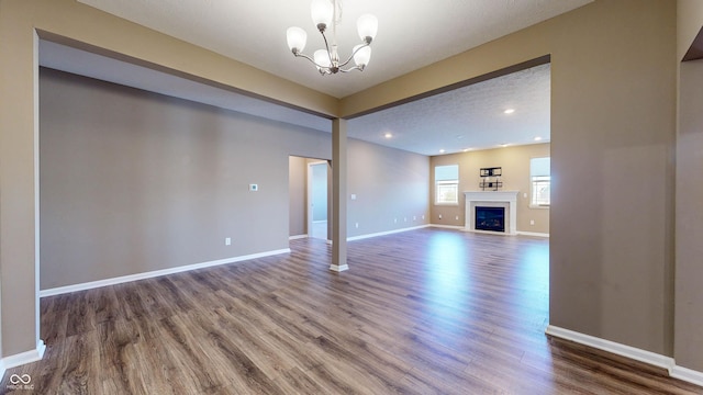 unfurnished living room with an inviting chandelier and hardwood / wood-style flooring