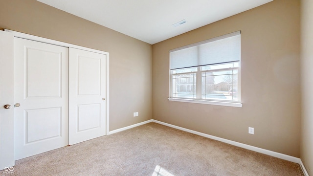 unfurnished bedroom with light carpet and a closet