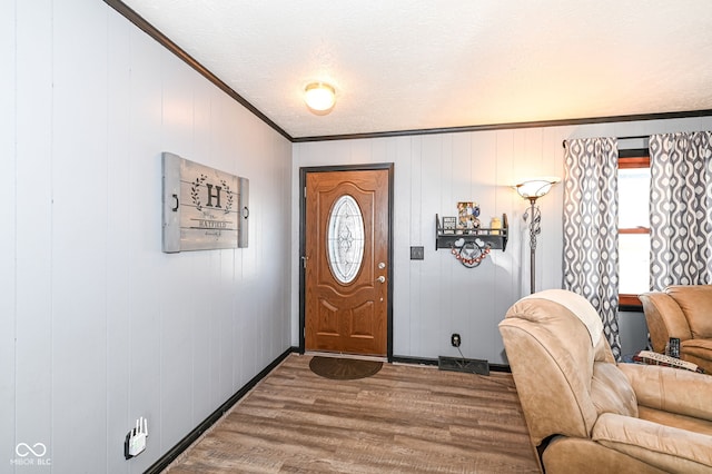 foyer featuring wood-type flooring, a textured ceiling, and crown molding