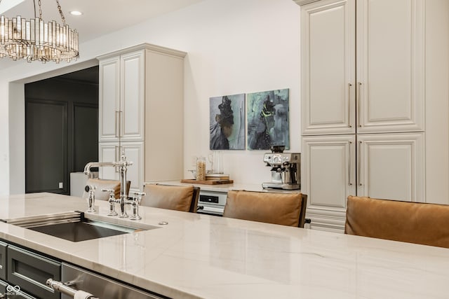 kitchen featuring light stone countertops, sink, an inviting chandelier, and decorative light fixtures