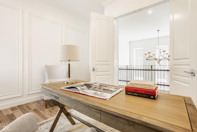 office area with a notable chandelier, ornamental molding, and light wood-type flooring