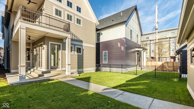 back of house with a balcony, a yard, and ceiling fan