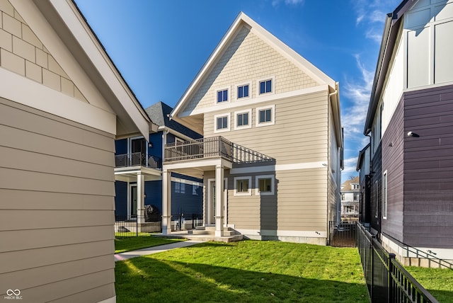 rear view of house featuring a yard and a balcony