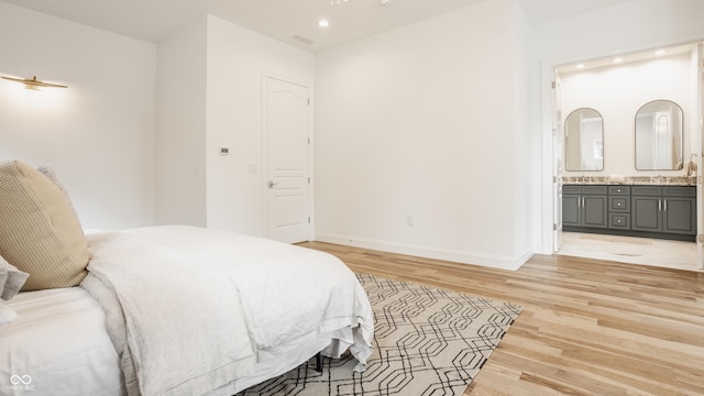 bedroom featuring connected bathroom and light hardwood / wood-style floors