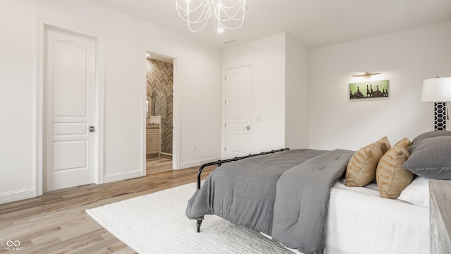 bedroom featuring an inviting chandelier, light hardwood / wood-style floors, and ensuite bathroom