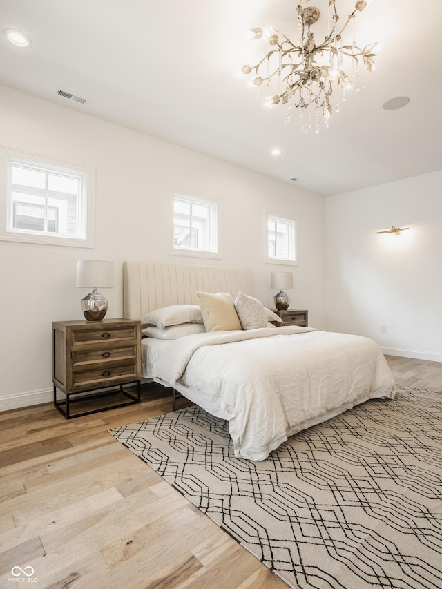 bedroom with an inviting chandelier and light hardwood / wood-style floors