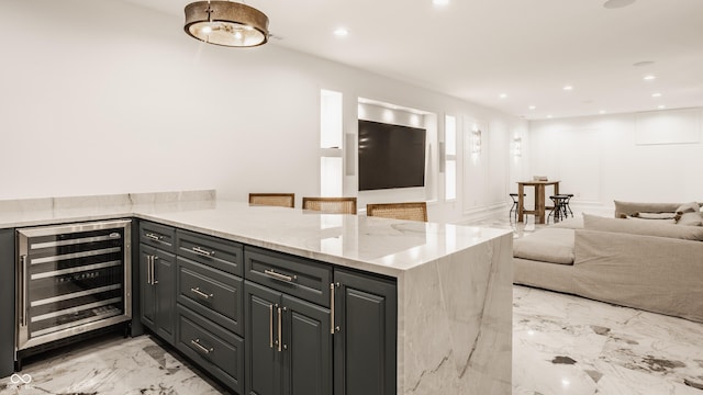 kitchen with light stone counters, beverage cooler, a breakfast bar, and kitchen peninsula