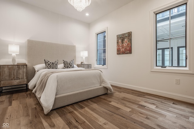 bedroom with multiple windows, hardwood / wood-style floors, and a notable chandelier