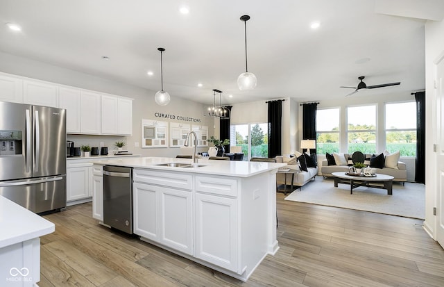 kitchen with an island with sink, sink, white cabinets, ceiling fan, and stainless steel appliances