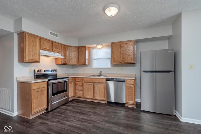 kitchen with stainless steel appliances, dark hardwood / wood-style floors, sink, and a textured ceiling