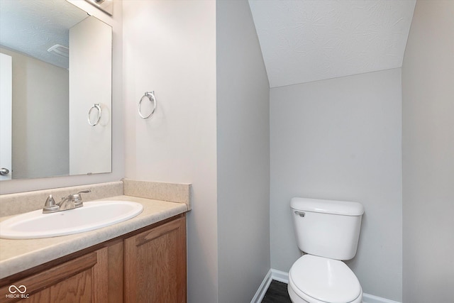 bathroom featuring vanity, a textured ceiling, and toilet