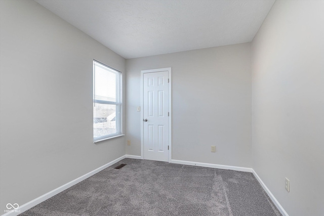 carpeted empty room featuring a textured ceiling