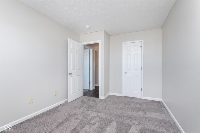 unfurnished bedroom featuring a textured ceiling and dark carpet