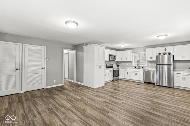 kitchen with sink, hardwood / wood-style flooring, stainless steel appliances, and white cabinets