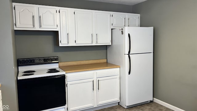 kitchen featuring white cabinetry, electric range, and white fridge