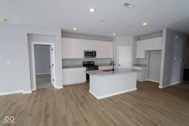 kitchen with a center island with sink, white cabinets, and appliances with stainless steel finishes