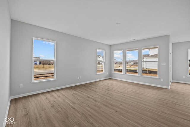 empty room with light hardwood / wood-style floors and a wealth of natural light