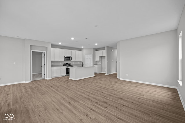 unfurnished living room featuring sink and light hardwood / wood-style flooring