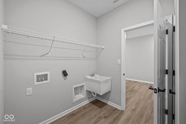 clothes washing area with light hardwood / wood-style flooring and hookup for a washing machine