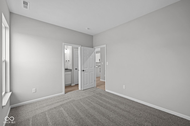 unfurnished bedroom featuring connected bathroom and carpet floors