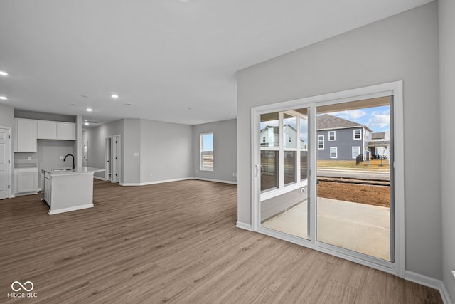 unfurnished living room featuring sink and light hardwood / wood-style floors