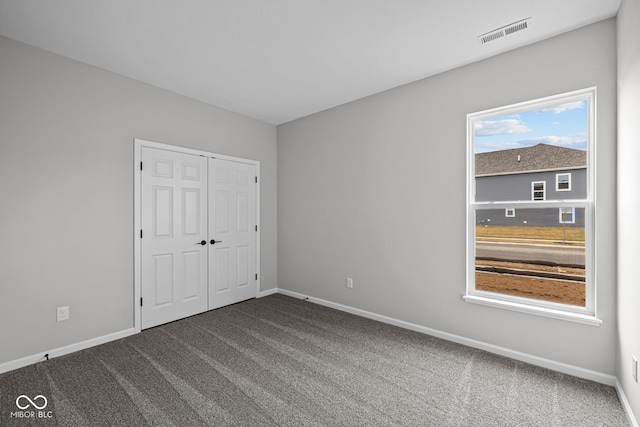 unfurnished bedroom featuring a closet and dark carpet