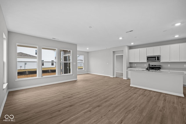 kitchen with white cabinets, appliances with stainless steel finishes, sink, and hardwood / wood-style flooring