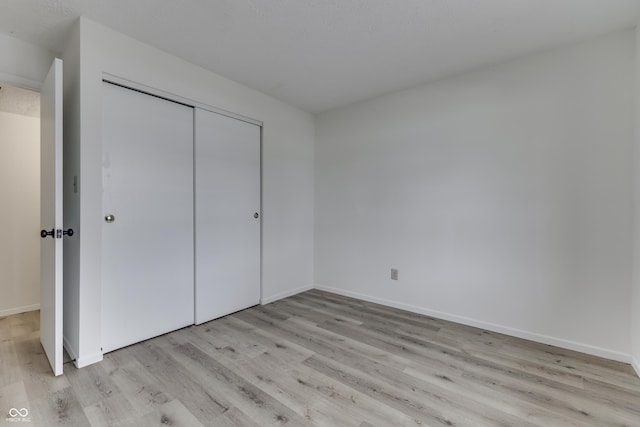 unfurnished bedroom with light wood-type flooring and a closet