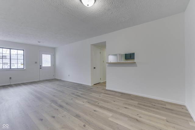 unfurnished room with a textured ceiling and light wood-type flooring