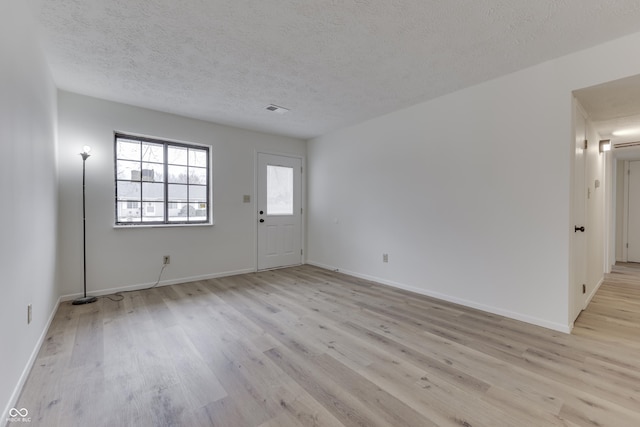 empty room featuring light hardwood / wood-style floors and a textured ceiling