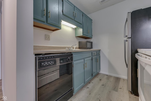 kitchen with blue cabinets, sink, light wood-type flooring, stainless steel fridge, and dishwasher