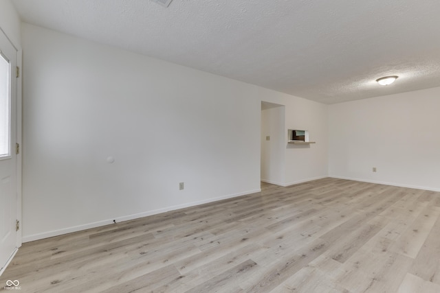 unfurnished room featuring a textured ceiling and light hardwood / wood-style flooring