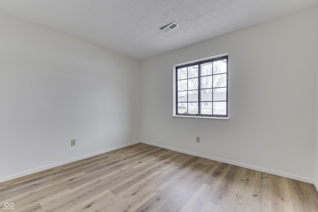 unfurnished room featuring light hardwood / wood-style floors and a textured ceiling