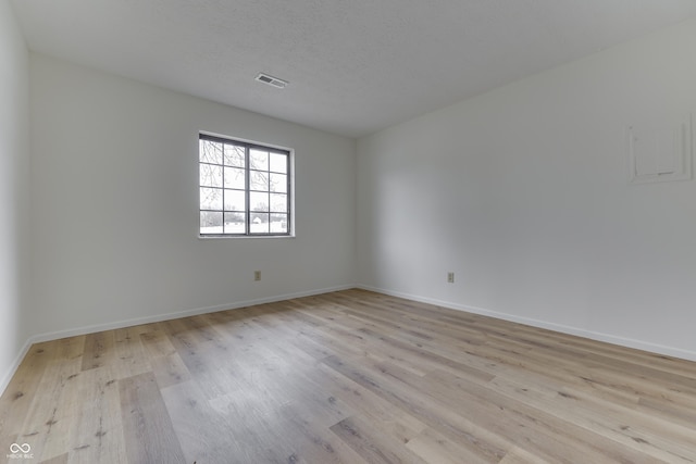 spare room featuring a textured ceiling and light wood-type flooring