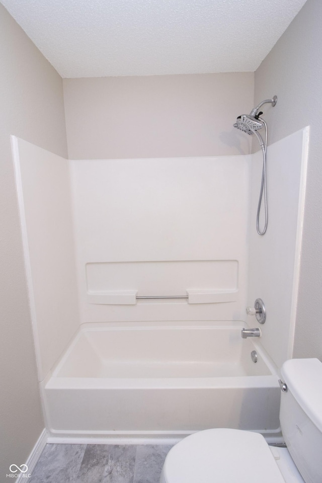 bathroom with shower / washtub combination, a textured ceiling, and toilet