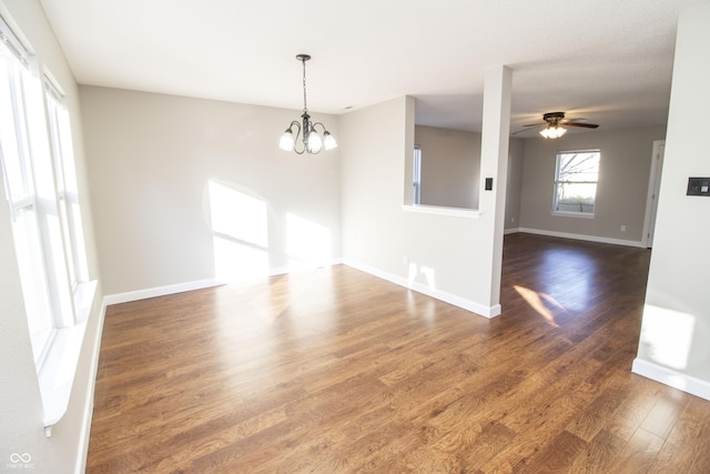 unfurnished room with ceiling fan with notable chandelier and dark wood-type flooring