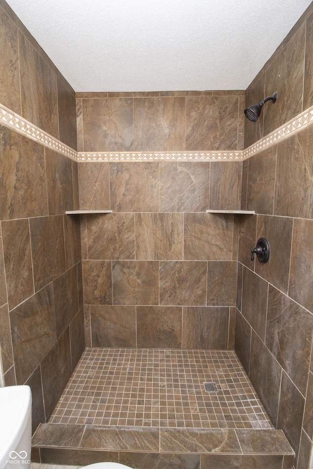 bathroom featuring a tile shower and toilet