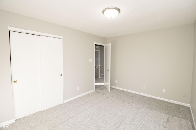 unfurnished bedroom featuring light colored carpet and a closet