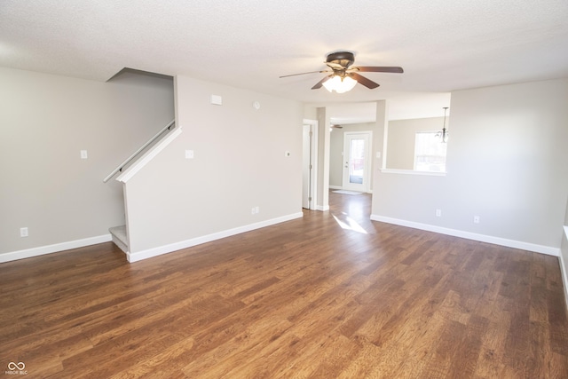 unfurnished living room featuring dark hardwood / wood-style flooring, ceiling fan, and a textured ceiling