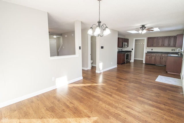 unfurnished dining area with dark hardwood / wood-style flooring, sink, and ceiling fan with notable chandelier