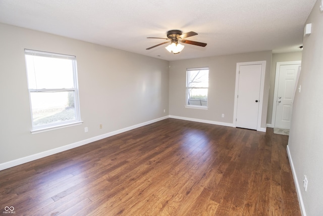 empty room with ceiling fan and dark hardwood / wood-style flooring