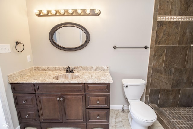 bathroom with tiled shower, vanity, and toilet