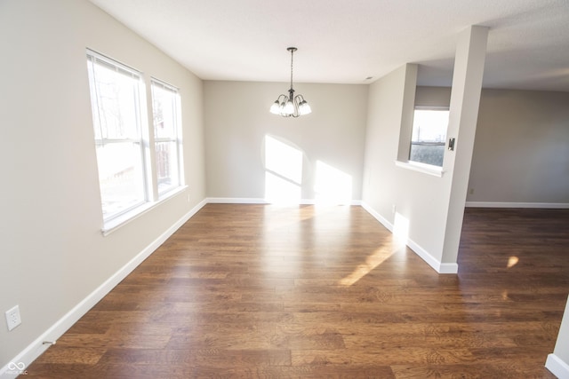 unfurnished dining area featuring dark hardwood / wood-style floors and an inviting chandelier