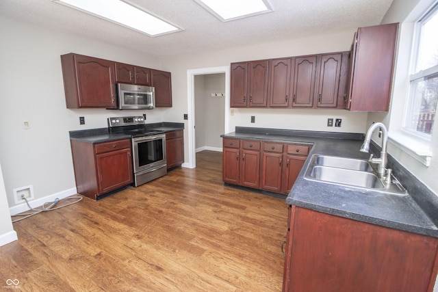 kitchen with appliances with stainless steel finishes, dark hardwood / wood-style floors, sink, and a textured ceiling